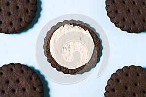 On a pastel blue background in the center lay a chocolate-cream cookie broken in half