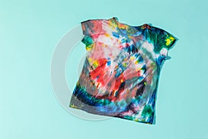 Pastel blue background and tie dye t-shirt. Flat lay.
