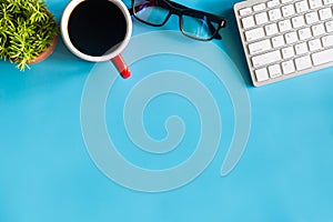 Pastel blue desk office with laptop, smartphone and other work supplies with cup of coffee. Top view with copy space for input the