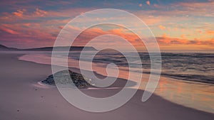 Pastel blue and pink clouds over the beach at sunset