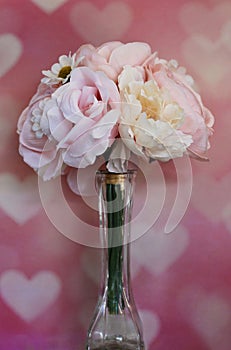 Pastel bouquet of flowers in a vase on a pink heart background, vertical