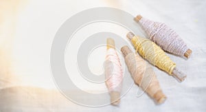 The pastel color embroidery thread roll using in garment industry put on the white cotton background, The sewing material selling