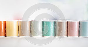 The pastel color embroidery thread spool using in garment industry, row of multicolored yarn rolls, sewing material selling in the