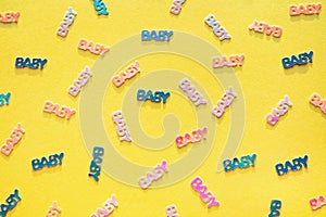 Pastel colored baby confetti on yellow background