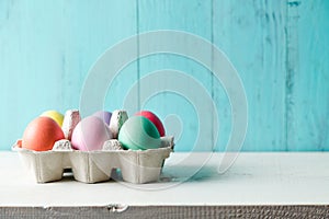 Pastel colored easter eggs in a egg box and turquoise background