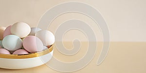 Pastel colored Easter eggs in white bowl on a table