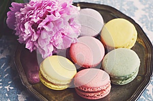 Pastel colored macaroons on a metal tray and peony flower photo