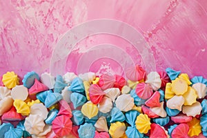 Pastel colored merengues cakes on pink background from above