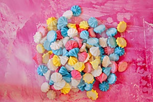 Pastel colored merengues cakes on pink background from above