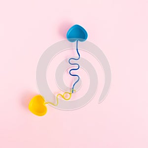 Pastel colored plastic dishes and drinking straws placed like clock hands on a pink background.