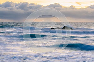 Pastel colors of sunset and silky water from long exposure of waves crashing by Pigeon Point Lighthouse on Northern California