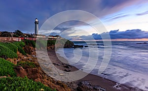 Pastel colors of sunset and silky water from long exposure of waves crashing by Pigeon Point Lighthouse on Northern California