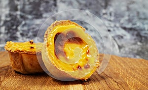 Pastel de nata tarts or Portuguese egg tart on a wooden brown background. Pastel de Belem is a small pie with a crispy