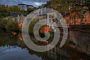 Pastel houses reflecting in Alzette river in Luxembourg old town, UNESCO World Heritage Site and the city wall at sunset