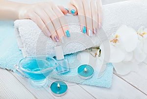 Pastel manicure with orchid and spa essentials. Combination of blue, white, pink colors and sparkles.