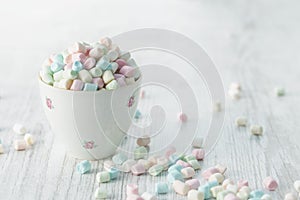 Pastel mini marshmallows in cup with painted little roses on white and grey underground HR SF