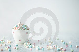 Pastel mini marshmallows in cup with painted pink roses on light white and grey underground HR SF