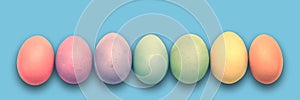 Pastel painted Easter eggs aligned in a row on blue panoramic background Easter web banner