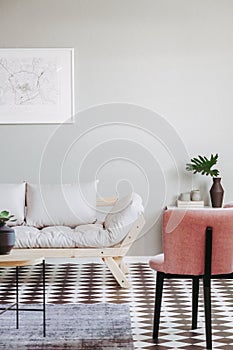Pink armchair and beige scandinavian futon in trendy living room interior with black and white floor