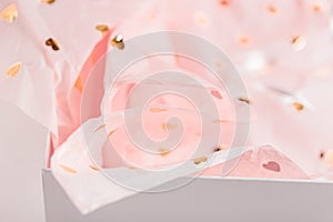 Pastel pink gift paper with golden hearts in white present box. Gift wrapping for special occasion. Valentine`s Day, Birthday