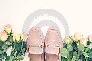 Pastel pink women shoes and roses on white background. Pair of elegant and stylish loafers. Flat lay, top view trendy