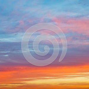 Pastel pink and yellow sunrise clouds in blue sky