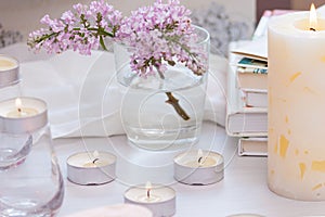 Pastel room interior decor with burning hand-made candle, books, flowers. Cozy and relax concept
