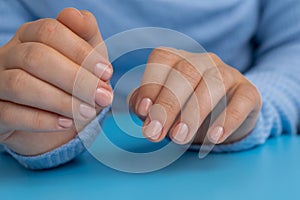 Pastel softness manicured nails on blue background. Woman showing her new manicure in colors of pastel palette