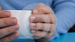 Pastel softness manicured nails on white cup on blue background. Woman showing her new manicure in colors of pastel