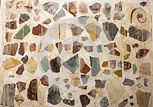 Pastel stucco wall fitted randomly with multicolor varied shaped stones