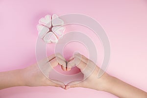 Pastel Valentine background is made of marshmallow souffle in the form of hearts on a pink background and a symbol of love made