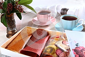 Pastilles in assortment in a box on a light background with two cups of tea. Fruit slices in the assortment. Copy of the space