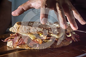 Pastrami sandwhich on a wooden tablet with delicious meet on baguette bread with cheese,copy space in parts of the image