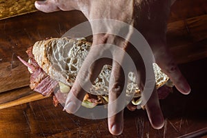 Pastrami sandwhich on a wooden tablet with delicious meet on baguette bread with cheese,copy space in parts of the image