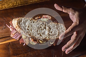 Pastrami sandwhich on a wooden tablet with delicious meet on baguette bread with cheese,copy space in parts of the image