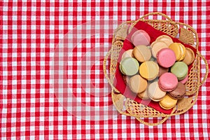 Pastries, desserts and sweets.  Top view of multicolord original french macaroon cookies are arranged in a basket on a red