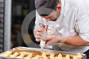 Pastry Chef with confectionary bag squeezing cream at pastry shop.