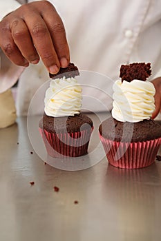 Pastry chef decorating chocolate cupcakes