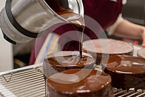 Pastry chef glazing chocolate cakes