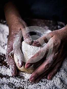 Pastry chef hand kneading Raw Dough with sprinkling white flour