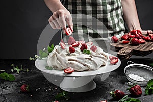 Pastry chef in the kitchen decorating cake Pavlova cake with fresh strawberries and whipped cream, culinary, bakery, food and