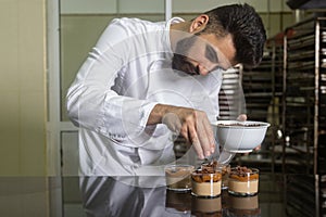 Pastry chef with mask working finishing a dessert in glass