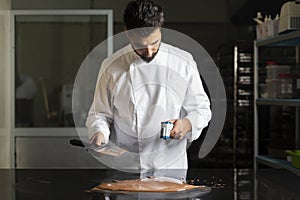 Pastry chef measuring the temperature of the chocolate with an infrared thermometer, working on the tempering of the chocolate photo