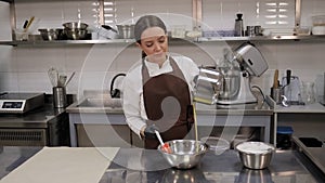 The pastry chef mixes pistachio mousse and whipped milk cream in a kitchen.