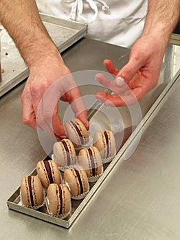 Pastry chef preparing chocolate macarons.