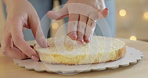 Pastry chef is putting cake sponge on cream to make a cake, hands closeup.