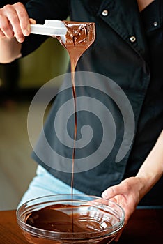 Pastry chef tempering hot dark chocolate. Cooking desserts. Soft selective focus