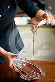 Pastry chef tempering hot dark chocolate. Cooking desserts. Soft selective focus