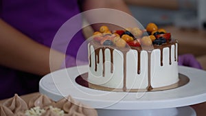 The pastry chef twists the cake stand to demonstrate its appearance.