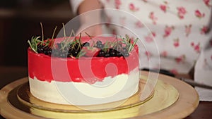 Pastry chef woman is presenting her layered creamy cake on rotating plate